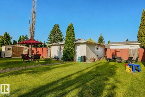 Expansive green lawn with mature trees, bordered by a privacy fence and featuring a detached storage shed - 3911 117 Street Nw, Edmonton, AB 
