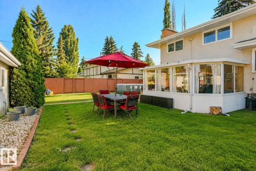 Expansive backyard with a manicured lawn, stone pathway, and mature trees - 3911 117 Street Nw, Edmonton, AB 