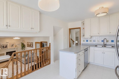 White kitchen cabinetry with stainless steel hardware, light-toned countertops, and a tiled backsplash - 3911 117 Street Nw, Edmonton, AB 