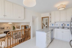 White kitchen cabinetry with stainless steel hardware, light-toned countertops, and a tiled backsplash - 