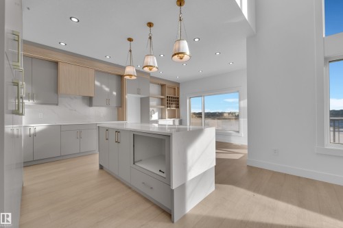 Kitchen featuring light wood-finish flooring, a large island with a waterfall countertop, recessed lighting, and pendant light fixtures - 226 Linden Loop, Leduc, AB 