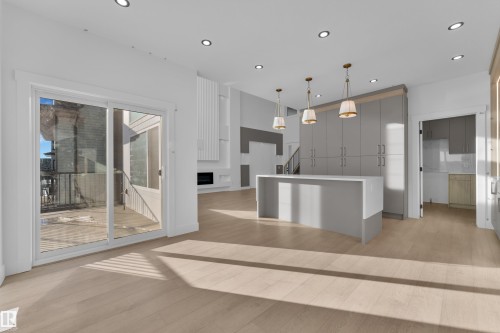 Light wood-finish flooring, recessed lighting, expansive sliding glass door, kitchen island with seating, and integrated gray cabinetry - 226 Linden Loop, Leduc, AB 