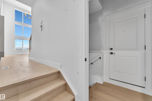 Light wood-finish flooring, white paneled door with black hardware, white walls, and a multi-pane window - 226 Linden Loop, Leduc, AB 