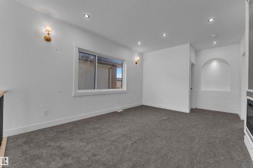 Recessed ceiling lighting, wall sconces, arched niche with accent lighting, built-in fireplace, and expansive window - 226 Linden Loop, Leduc, AB 