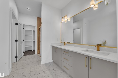 Double vanity with integrated sinks, gold-finish fixtures, quartz countertops, and a full-width framed mirror - 226 Linden Loop, Leduc, AB 