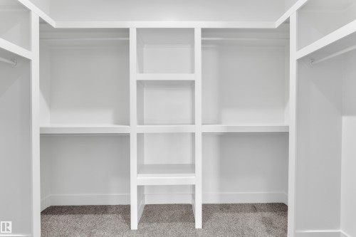 Built-in closet system featuring white shelving and hanging rods over gray carpet - 226 Linden Loop, Leduc, AB 