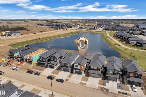Aerial perspective showcasing a developed residential area with a central water feature, surrounded by detached homes with attached garages - 226 Linden Loop, Leduc, AB 