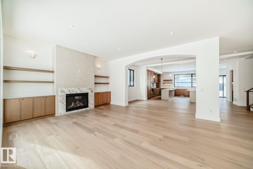 Hardwood-finish flooring throughout, integrated built-in shelving, fireplace with stone surround, recessed lighting, and an arched entryway - 10514 134 Street Nw, Edmonton, AB 