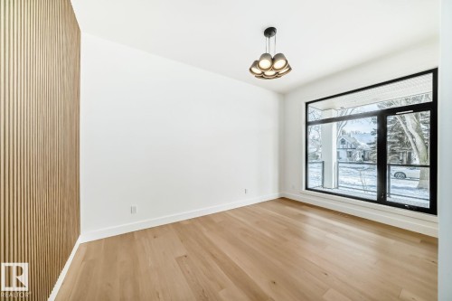 Wide plank wood-finish flooring, full-height accent wall with vertical slat detailing, contemporary ceiling fixture, and expansive window - 10514 134 Street Nw, Edmonton, AB 