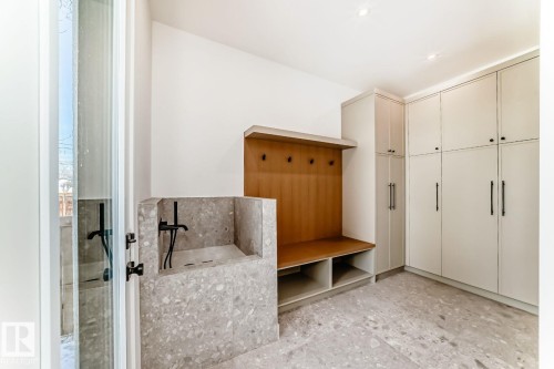 Terrazzo-style flooring, built-in mudroom storage bench, black wall-mounted faucet, custom cabinetry with dark hardware, recessed ceiling lighting - 10514 134 Street Nw, Edmonton, AB 