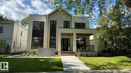 Modern architecture featuring a stone and stucco exterior, black-framed windows, a covered front porch, and a concrete walkway - 10514 134 Street Nw, Edmonton, AB 
