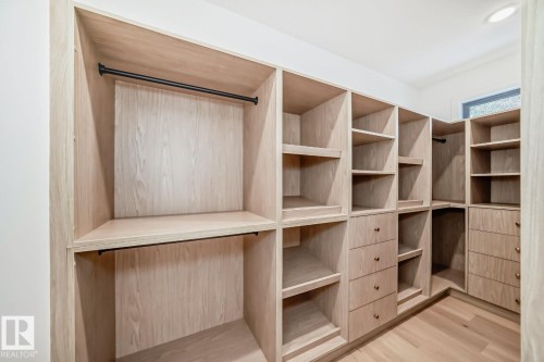 Built-in shelving with light wood-finish cabinetry, integrated drawers, hanging rods, and wood-finish flooring - 10514 134 Street Nw, Edmonton, AB 