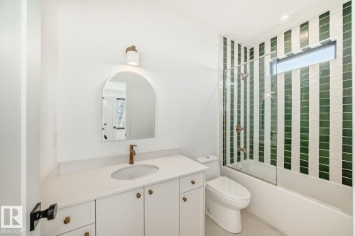 White vanity with an integrated sink, arch-top mirror, and wall-mounted lighting - 10514 134 Street Nw, Edmonton, AB 