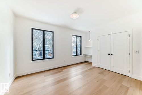 Hardwood flooring, dual pane windows with black frames, built-in shelving, white paneled double doors, and a flush mount ceiling light - 10514 134 Street Nw, Edmonton, AB 