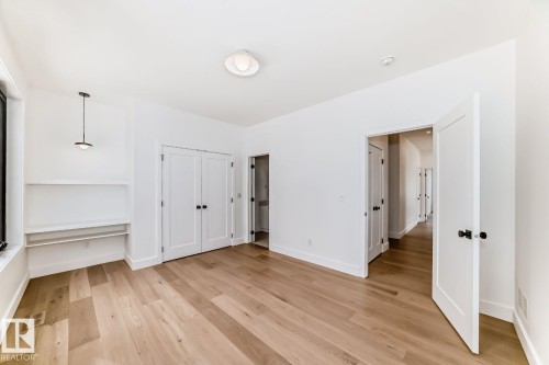 Wood-finish flooring, built-in shelving, white paneled doors, and contemporary light fixtures - 10514 134 Street Nw, Edmonton, AB 
