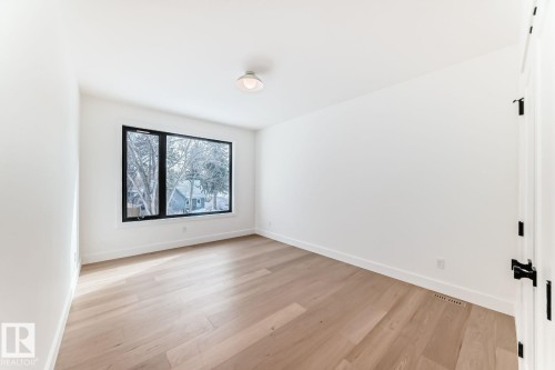 Expansive window with black trim, wood-finish flooring, white walls, and a ceiling-mounted light fixture - 10514 134 Street Nw, Edmonton, AB 