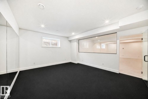 Spacious room featuring dark-toned carpeting, recessed lighting, and a glass-paneled partition - 10514 134 Street Nw, Edmonton, AB 