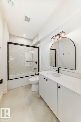 White vanity with integrated sink, black faucet, and arched mirror - 10514 134 Street Nw, Edmonton, AB 