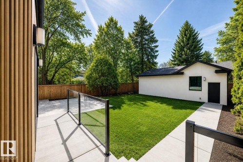 Private backyard featuring a well-maintained lawn, privacy fencing, and mature trees - 10514 134 Street Nw, Edmonton, AB 