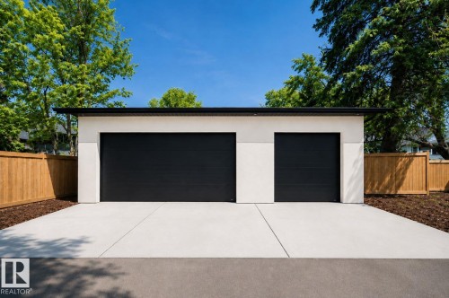 Two-car garage with black doors, white stucco exterior, and a flat black roofline - 10514 134 Street Nw, Edmonton, AB 