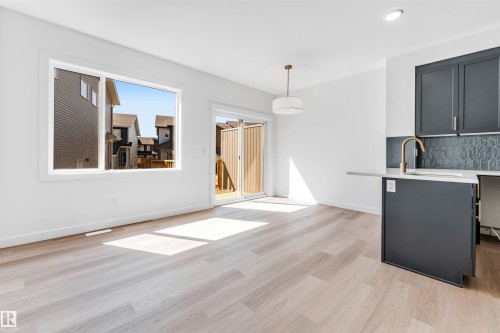 Light wood-finish flooring, a large window, and sliding glass doors - #48 710 Mattson Dr Sw Sw, Edmonton, AB 