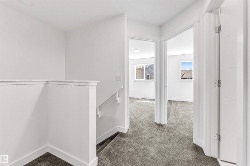 Upper hallway featuring light gray carpeting, white walls, white trim, and white doors - #48 710 Mattson Dr Sw Sw, Edmonton, AB 