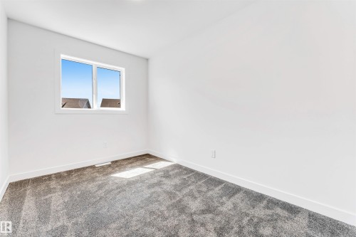 Bright corner bedroom showcasing new carpeting, clean white walls, and dual casement windows with natural light and exterior visibility - #48 710 Mattson Dr Sw Sw, Edmonton, AB 