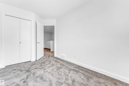 Plush gray carpeting, white walls, and a white bi-fold closet door with chrome hardware - #48 710 Mattson Dr Sw Sw, Edmonton, AB 