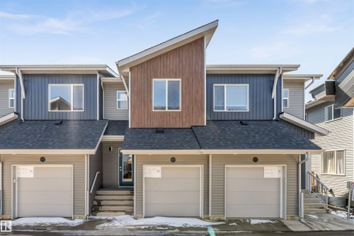Multi-level exterior with a prominent front entrance, multiple windows, attached garages, and a dark asphalt shingle roof - #48 710 Mattson Dr Sw Sw, Edmonton, AB 