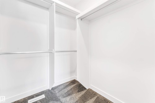 Walk-in closet with multiple hanging rods, white shelving, and grey carpeting - #48 710 Mattson Dr Sw Sw, Edmonton, AB 