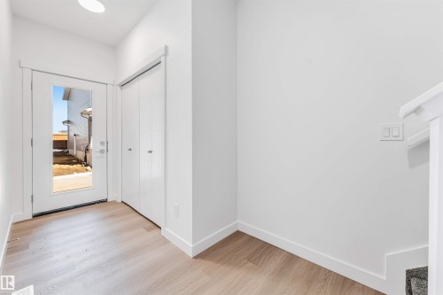 Entryway featuring wood-finish flooring, a full-lite exterior door, and a built-in closet with bi-fold doors - #48 710 Mattson Dr Sw Sw, Edmonton, AB 
