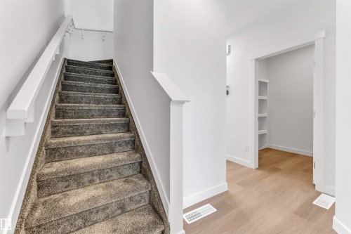 Carpeted staircase with white handrail and wall-mounted coat rack - #48 710 Mattson Dr Sw Sw, Edmonton, AB 