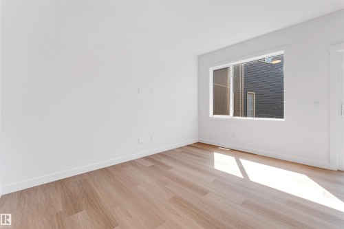 Light wood-finish flooring with white walls and trim, featuring a large window - #48 710 Mattson Dr Sw Sw, Edmonton, AB 