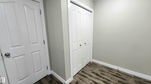 Paneled interior doors, bifold closet doors, wood-finish flooring, and light-toned walls - #101 11803 22 Av Sw, Edmonton, AB 