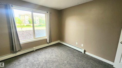 Carpeted flooring, neutral wall paint, white trim, sliding window, and white door - #101 11803 22 Av Sw, Edmonton, AB 
