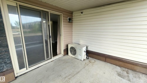 Sliding glass door, concrete patio, horizontal vinyl siding, exterior wall light fixture, stone veneer accent - #101 11803 22 Av Sw, Edmonton, AB 