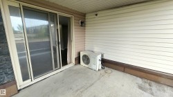 Sliding glass door, concrete patio, horizontal vinyl siding, exterior wall light fixture, stone veneer accent - 
