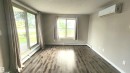 Wood-finish flooring, sliding glass door, additional window, baseboard heating, and a wall-mounted climate control unit - #101 11803 22 Av Sw, Edmonton, AB 