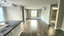 Spacious main living area featuring dark wood-finish flooring, light grey walls, and abundant natural light from multiple windows - #101 11803 22 Av Sw, Edmonton, AB 