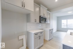 Kitchen featuring light gray cabinetry, white subway tile backsplash, white countertops, and wood-finish flooring - 