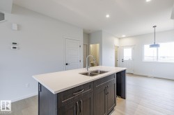 Kitchen island featuring a dual basin sink with a gooseneck faucet, light-toned countertop, and dark wood-finish cabinetry - 