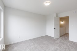 Spacious room featuring light gray carpeting, neutral wall paint, and a modern ceiling light fixture - 