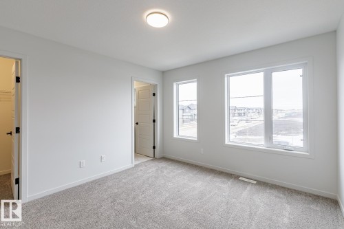 Bright room featuring multiple large windows, neutral-toned carpeting, white walls, and a contemporary ceiling light fixture - 70 Dansereau Way, Beaumont, AB - Indoor Photo Showing Other Room