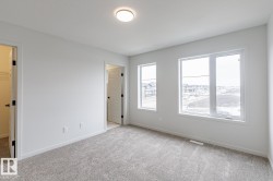 Bright room featuring multiple large windows, neutral-toned carpeting, white walls, and a contemporary ceiling light fixture - 