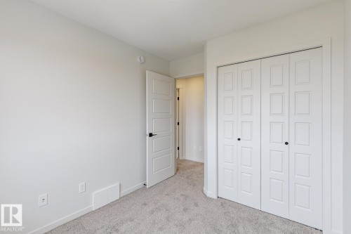 Room featuring light gray carpeting, neutral wall paint, and a white paneled door with black hardware - 70 Dansereau Way, Beaumont, AB - Indoor