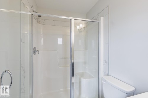 Glass-enclosed shower with chrome hardware, an integrated shower seat, and white paneling - 70 Dansereau Way, Beaumont, AB - Indoor Photo Showing Bathroom
