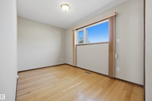 Wood-finish flooring, neutral wall tones, and a window with wood trim - 14008 94 Street Nw, Edmonton, AB 