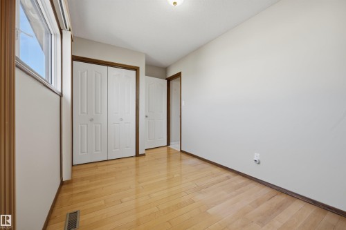 Hardwood flooring, white bi-fold closet doors, white walls, white trim around windows, and a doorway - 14008 94 Street Nw, Edmonton, AB 