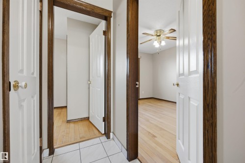 White paneled doors with brass-toned hardware, wood-finish flooring, and a ceiling fan with integrated lighting - 14008 94 Street Nw, Edmonton, AB 