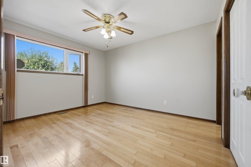 Bright room with wood-finish flooring, a multi-pane window, and a ceiling fan with integrated lighting - 14008 94 Street Nw, Edmonton, AB 